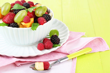 Fruit salad in bowl, on wooden background