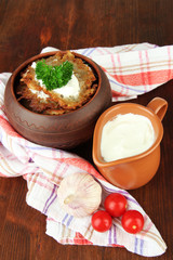 Potato pancakes in pot, on wooden background