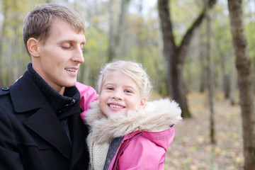 Happy father and daughter in autumn forest.