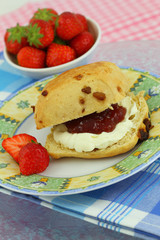 Scone with strawberry jam and clotted cream, close up