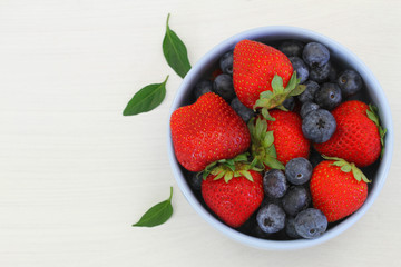 Strawberries and blueberries in bowl with copy space