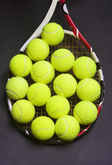 Tennis Racket with a lot of Tennis balls on it