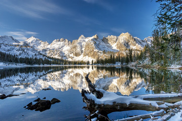 Winter mountain lake with log and reflections