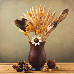Dried flowers in wooden vase with pine corn