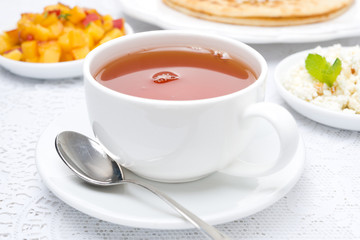 cup of black tea and fresh breakfast in the background