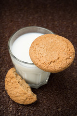 glass of milk and oat cookies on a dark background