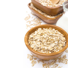 Oat flakes in wooden bowl and a jug of milk, isolated
