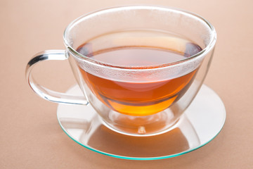 transparent cup of black tea on a brown background