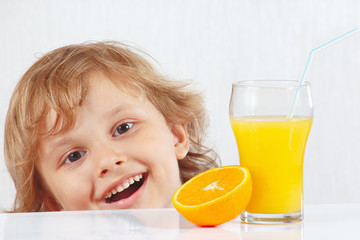 Beautiful smiling child with a glass of fresh juice and orange