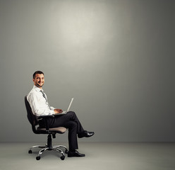 man with laptop sitting in grey room