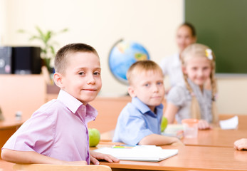 Fototapeta premium Portrait of schoolchild at workplace with teacher on background