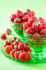 Ripe strawberry in a green vase on a table.