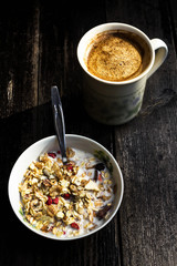 Rustic Breakfast with muesli and cup of coffee on old dark woode
