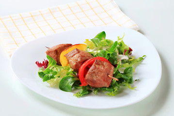 Grilled pork skewer with salad greens