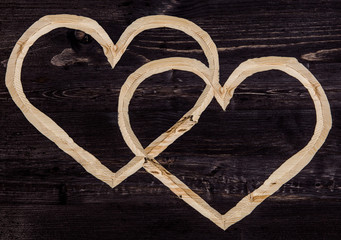 Сarved crossing hearts on dark wood background