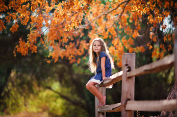 Pretty little girl relax on beauty autumn landscape background