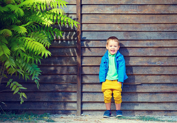 happy fashionable boy in front of wooden wall