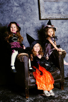 group of three little girl wearing in witch costumes celebrate H