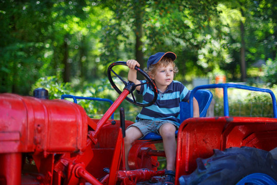 Portrait of little blond boy in tractor in summer