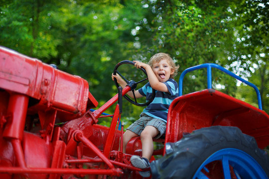 Portrait of little blond boy in tractor in summer