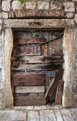 Old boarded up door in gray stone wall