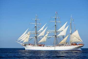 old historical tall ship with white sails in blue sea