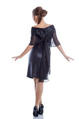 Slim girl posing in cocktail dress, back to camera