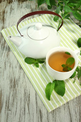 Teapot and cup of herbal tea with fresh mint flowers