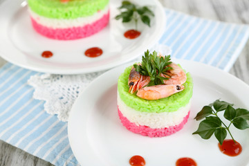 Colored rice on plates on napkin on wooden table