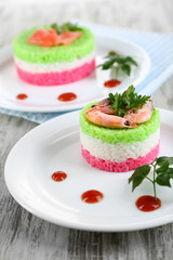 Colored rice on plates on napkin on wooden table