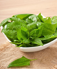 washed spinach leaves in a bowl on a wooden table