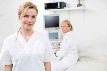Happy Female Gynecologist With Colleague In Background