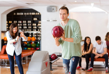Man Bowling With Friend Photographing in Club