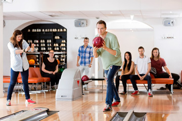 Fototapeta premium Man Bowling With Friend Photographing At Club