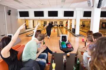 Naklejka premium Friends Cheering Woman Bowling in Club