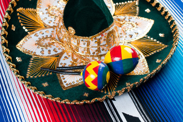 Mexican sombrero and maracas on a striped poncho