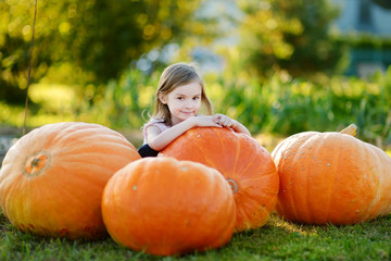 Adorable little girl embracing big pumpkin