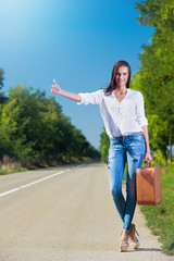 Beautiful woman hitchhiking with suitcase