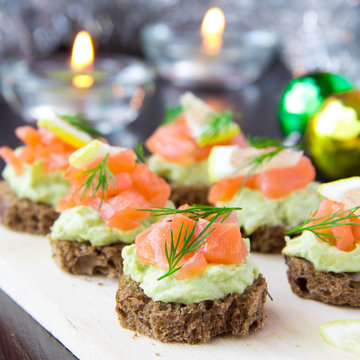 Appetizer canapes of bread with avocado, red fish salmon, lemon,