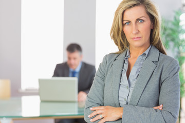 Obraz premium Unsmiling businesswoman looking at camera crossed arms with a bu