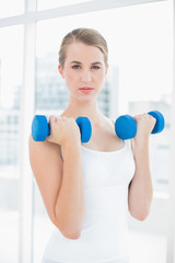 Content fit woman exercising with dumbbells