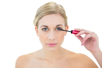 Concentrated young blonde woman applying mascara