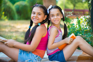 Sisters reading book in summer park