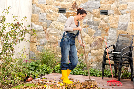 Young Woman Sweeping Autumn Leaves Veranda