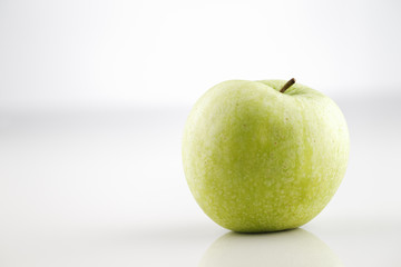 An image of a green apple with stem on a white background
