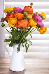 Flowers in a vase with sun light coming out of window blinds