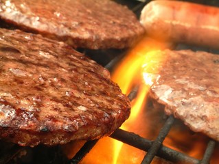 burgers and sausage cooking on Barbecue