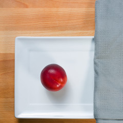 red ripe nectarine peaches on white plate