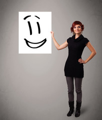 Young woman holding smiley face drawing