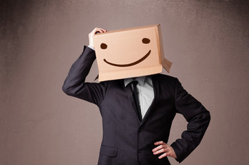 Businessman gesturing with a cardboard box on his head with smil